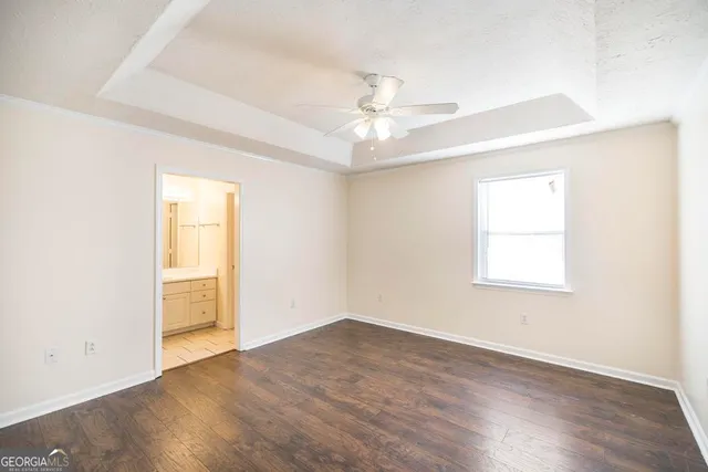 an empty room with wooden floor chandelier fan and windows