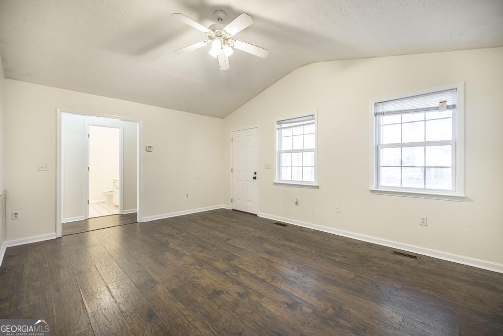 411 Cypress Drive Dublin, GA 31021 - Photo 8 of 31 an empty room with wooden floor ceiling fan and windows
