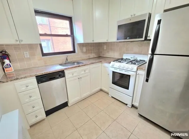 a kitchen with white cabinets appliances and sink