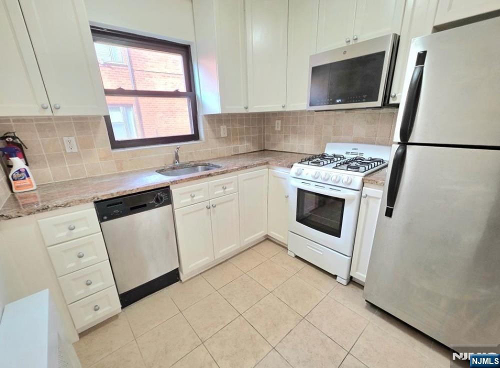 2173 North Central Road, Unit C Fort Lee, NJ 07024 - Photo 3 of 11 a kitchen with white cabinets appliances and sink