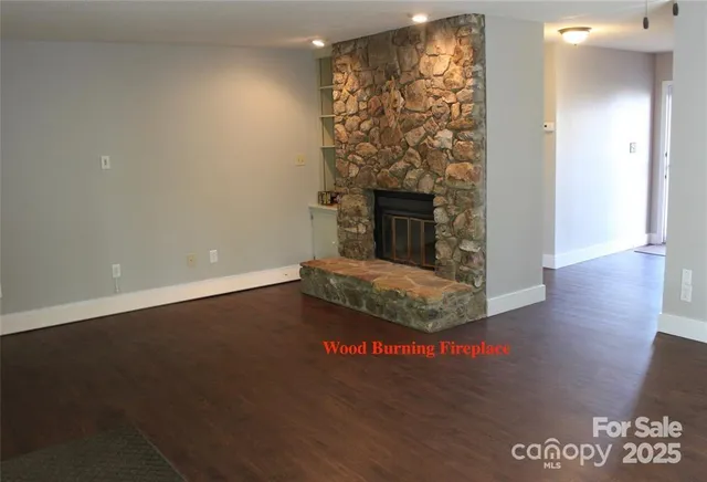 an empty room with wooden floor fireplace and windows