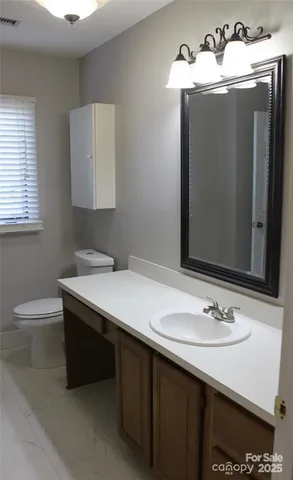 a bathroom with a sink vanity granite and a toilet
