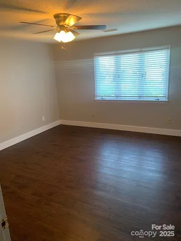 an empty room with wooden floor fan and windows