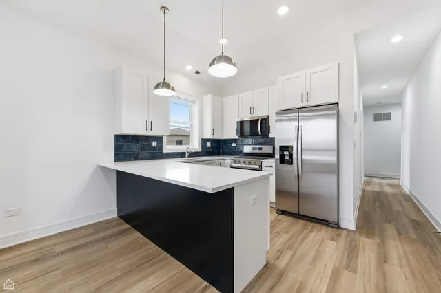 a kitchen with kitchen island a counter space a sink appliances and cabinets