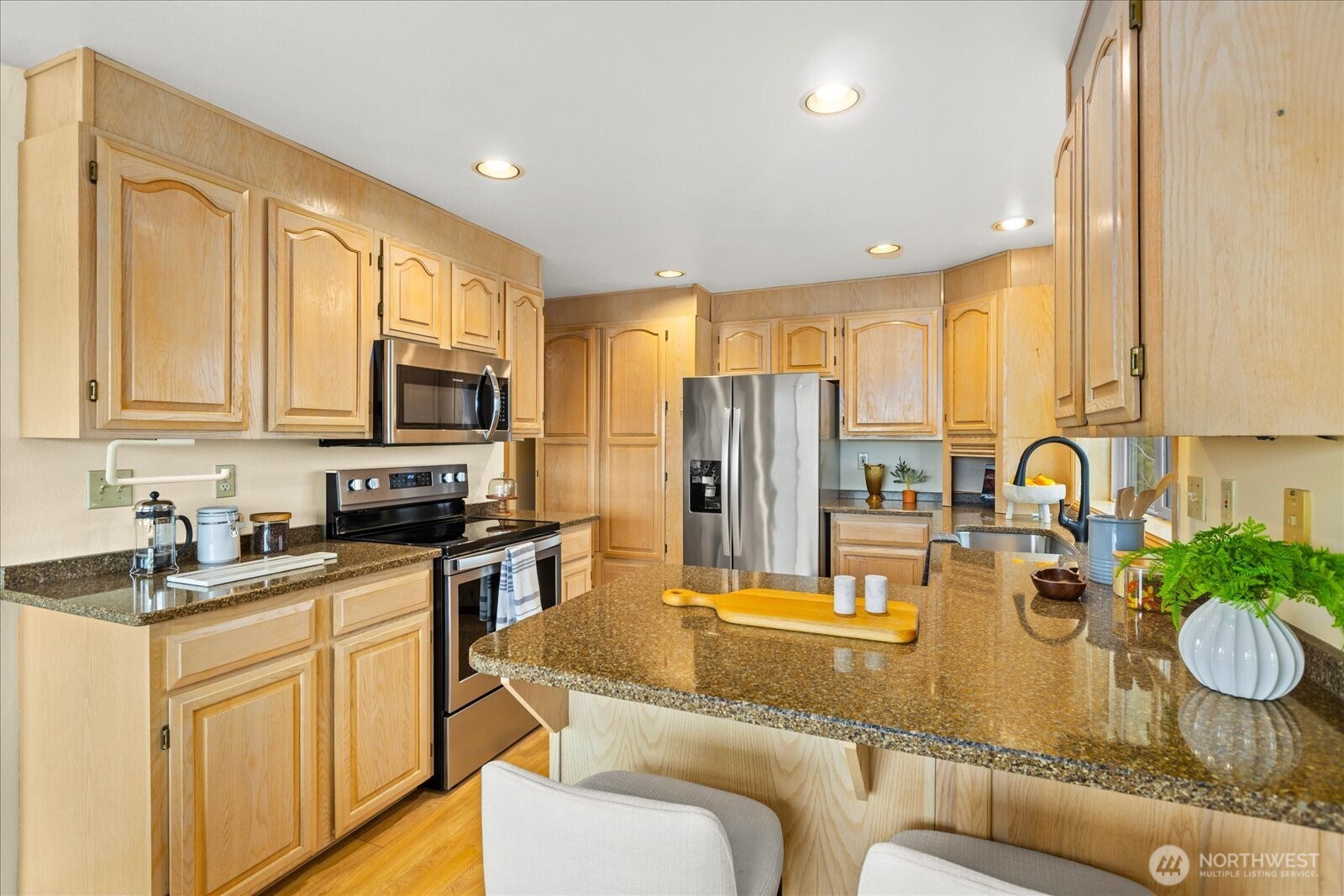 233 3rd Avenue South, Unit 305 Edmonds, WA 98020 - Photo 14 of 34 a kitchen with stainless steel appliances granite countertop a refrigerator a stove top oven a sink dishwasher and white cabinets with wooden floor