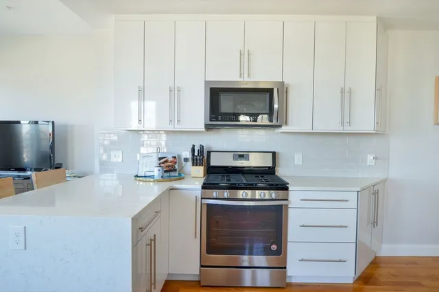 a kitchen with white cabinets and a stove with a sink