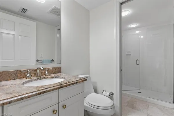 a bathroom with a granite countertop sink a toilet and shower