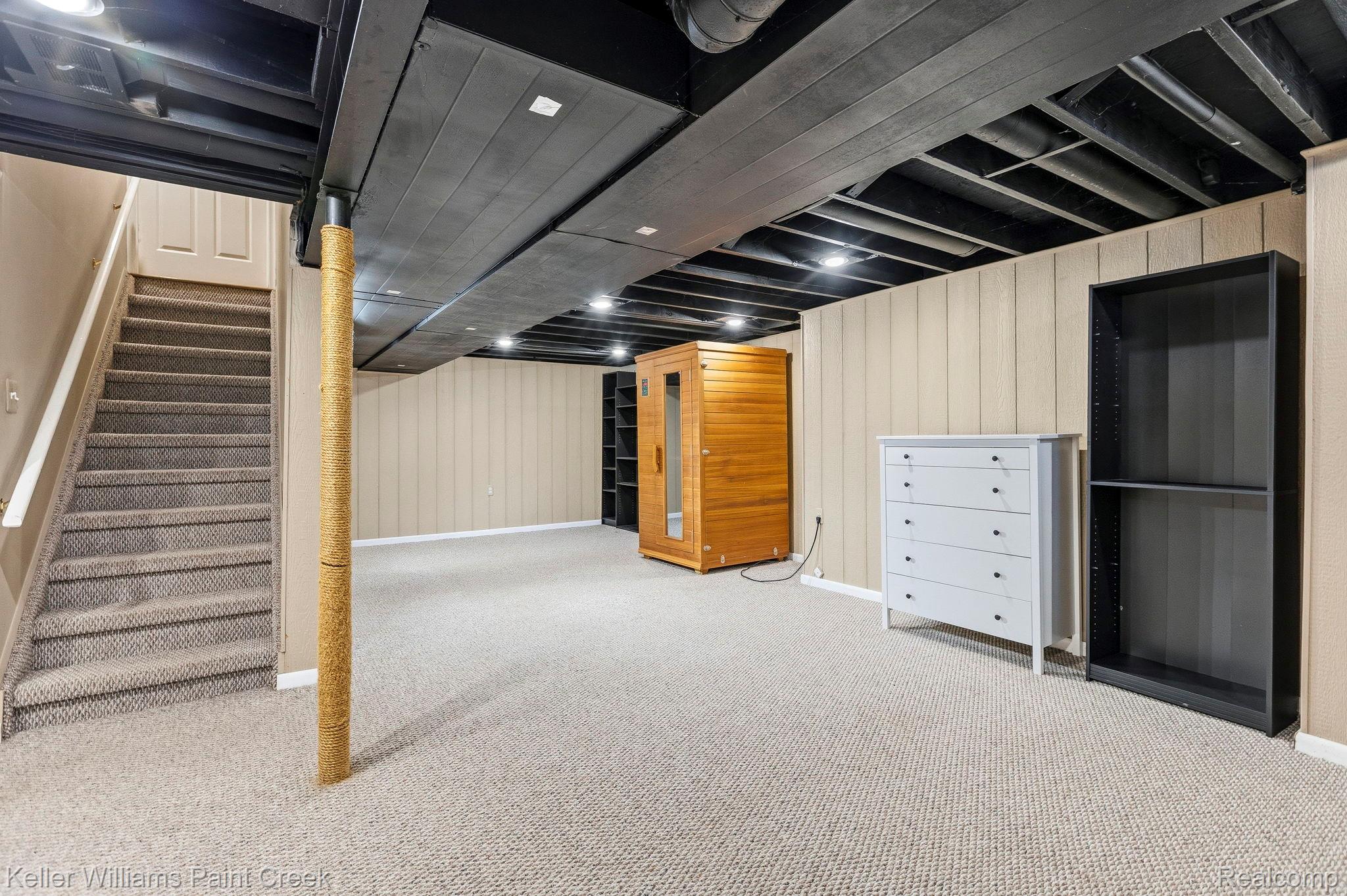 1675 North Kilburn Road Rochester, MI 48306 - Photo 44 of 48 Finished lower level featuring recessed lighting, a carpeted staircase with white handrails, and neutral-toned wall paneling