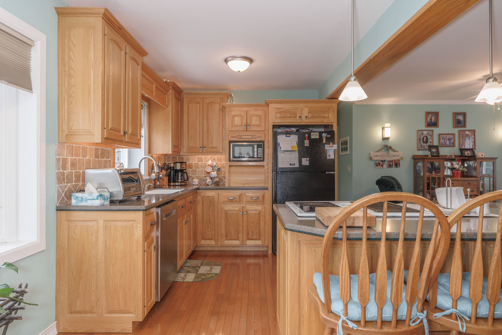 305 Granada Road Bloomington, IL 61701 - Photo 10 of 36 a kitchen with stainless steel appliances kitchen island granite countertop a refrigerator a stove a sink dishwasher and wooden cabinets with wooden floor