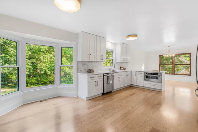 a kitchen with stainless steel appliances a white cabinets and wooden floor