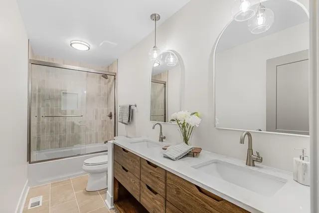 a bathroom with a double vanity sink mirror double shower and a toilet