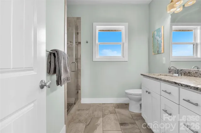 a bathroom with a granite countertop sink toilet and shower