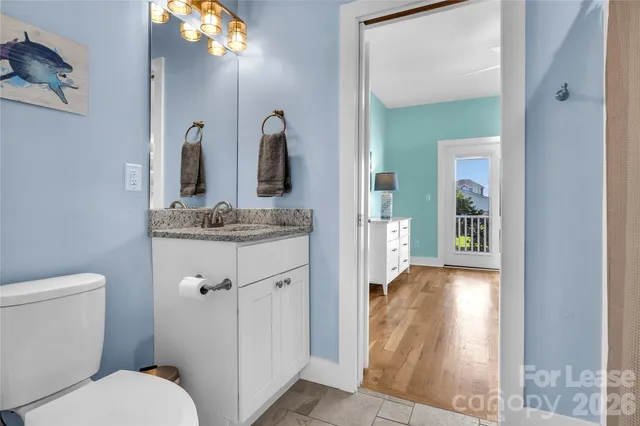 a bathroom with a granite countertop sink vanity mirror and toilet