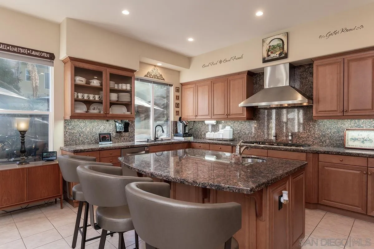 16333 Deer Ridge Road San Diego, CA 92127 - Photo 9 of 43 a kitchen with stainless steel appliances granite countertop a sink a stove and a wooden cabinets