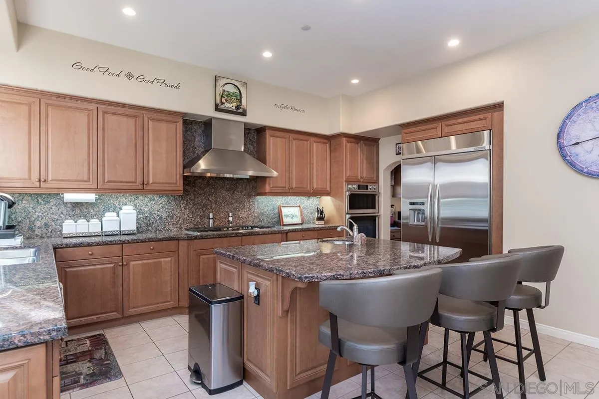 16333 Deer Ridge Road San Diego, CA 92127 - Photo 10 of 43 a kitchen with stainless steel appliances granite countertop a kitchen island a table and chairs in it
