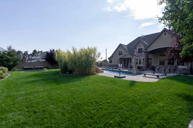 687 South 2080th Street East Springville, UT 84663 - Photo 96 of 149 Expansive green lawn with mature landscaping, a stone and stucco exterior, an outdoor swimming pool, and a paved patio area