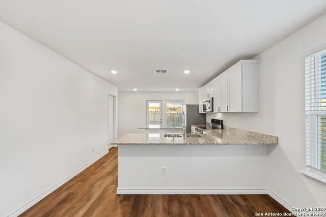 a kitchen with kitchen island a sink wooden floor and counter top space