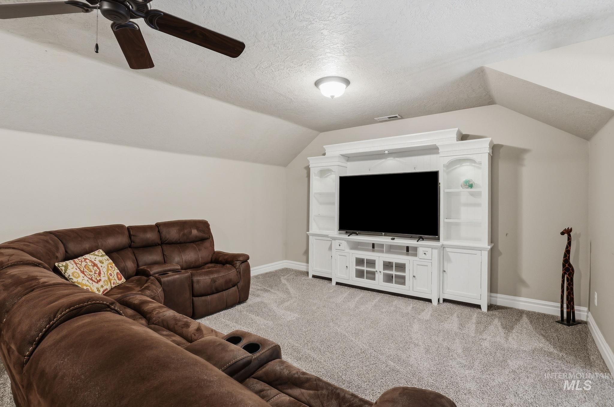 3969 North Hollymount Way Meridian, ID 83646 - Photo 32 of 47 Spacious room featuring sloped ceilings, light-toned carpeting, and a built-in entertainment center with open shelving and cabinet storage
