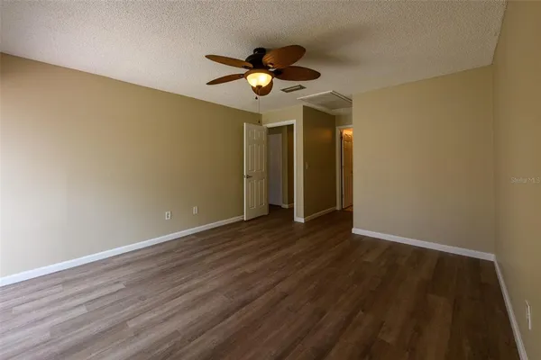 a view of a room with wooden floor ceiling fan and window