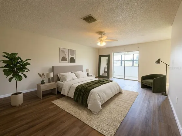 a spacious bedroom with a bed a couch and a potted plant