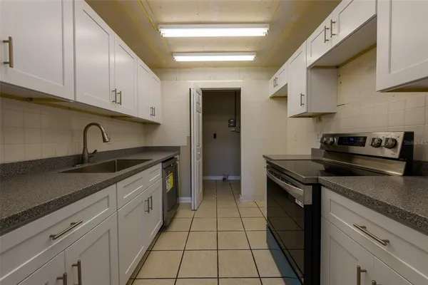 a kitchen with granite countertop a sink dishwasher stove and cabinets