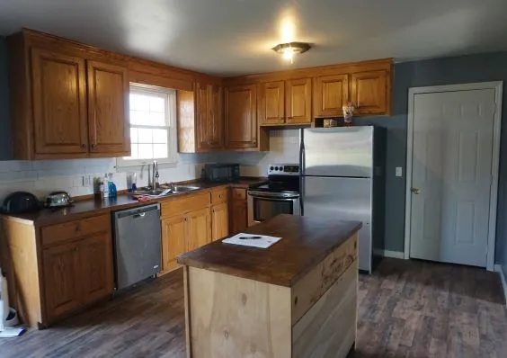 a kitchen with stainless steel appliances granite countertop a refrigerator a sink a stove a counter space and cabinets