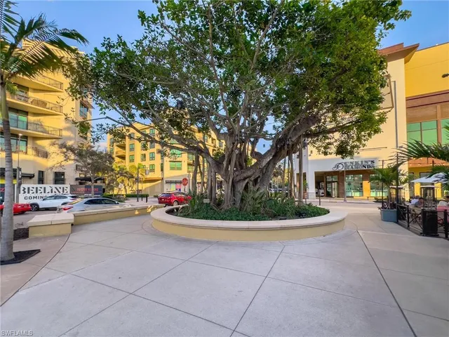 a view of road with card parked on side and retail shops