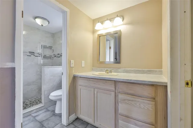 a bathroom with a granite countertop sink mirror and a toilet
