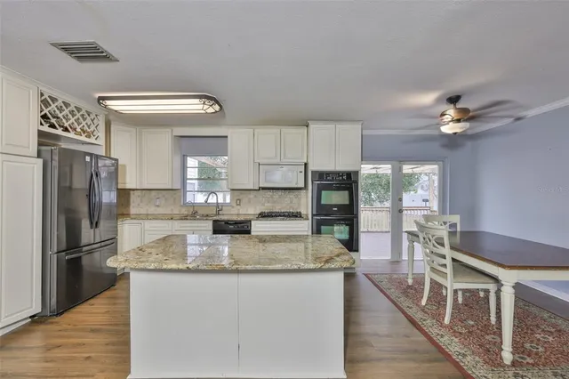 a kitchen with stainless steel appliances granite countertop a sink refrigerator and cabinets