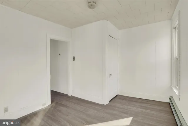 a view of an empty room with wooden floor and a bathroom