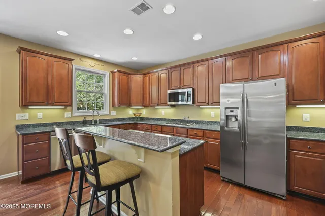 a kitchen with stainless steel appliances granite countertop a refrigerator and a stove top oven