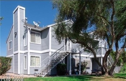 Back of property with a chimney, a lawn, and stairway