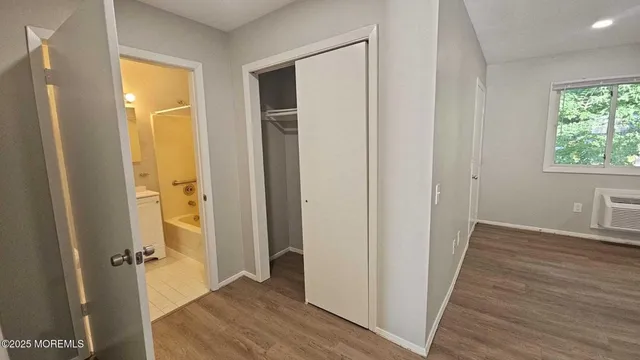 a view of a hallway with wooden floor and a bathroom