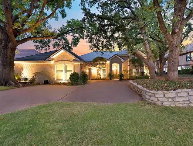 a front view of a house with a yard and large trees
