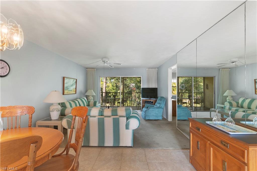 499 Forest Lakes Boulevard, Unit 2304 Naples, FL 34105 - Photo 11 of 21 a living room with furniture a large window and potted plants
