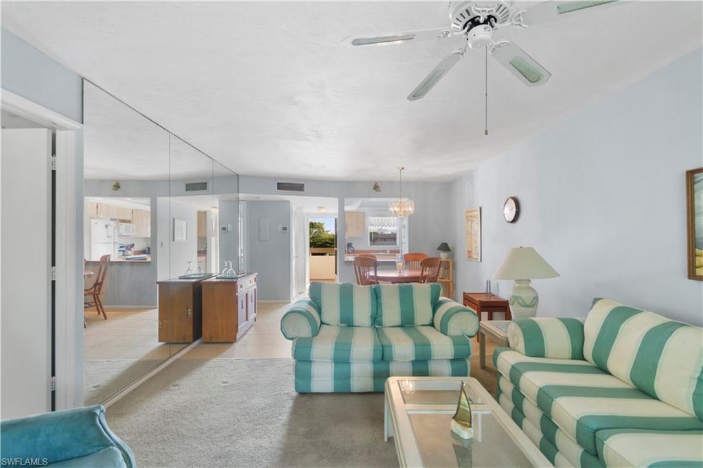 499 Forest Lakes Boulevard, Unit 2304 Naples, FL 34105 - Photo 13 of 21 a living room with furniture and a chandelier