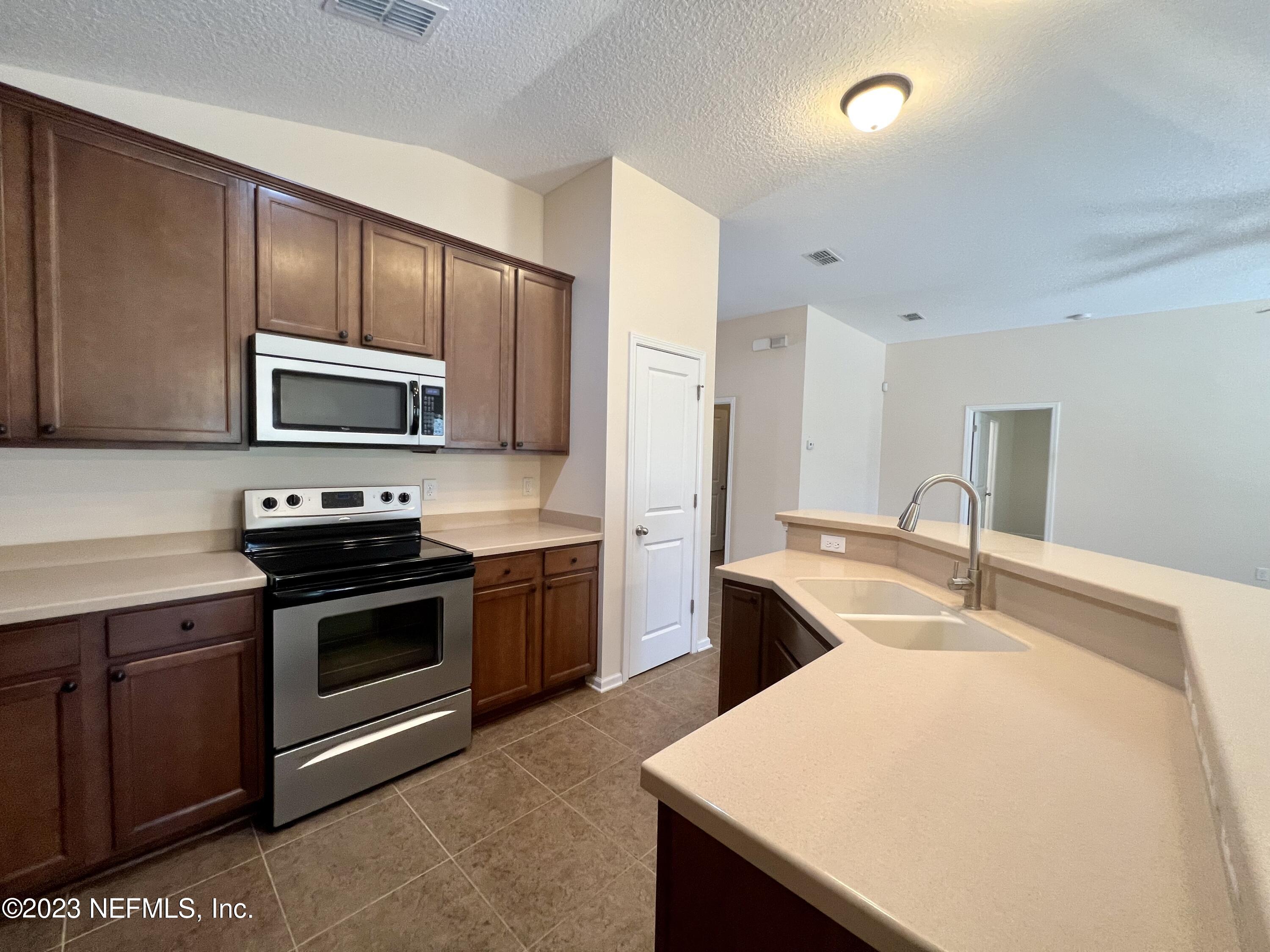 120 East Franchetta Lane St. Augustine, FL 32092 - Photo 11 of 25 a kitchen with stainless steel appliances a stove a sink a microwave and wooden cabinets