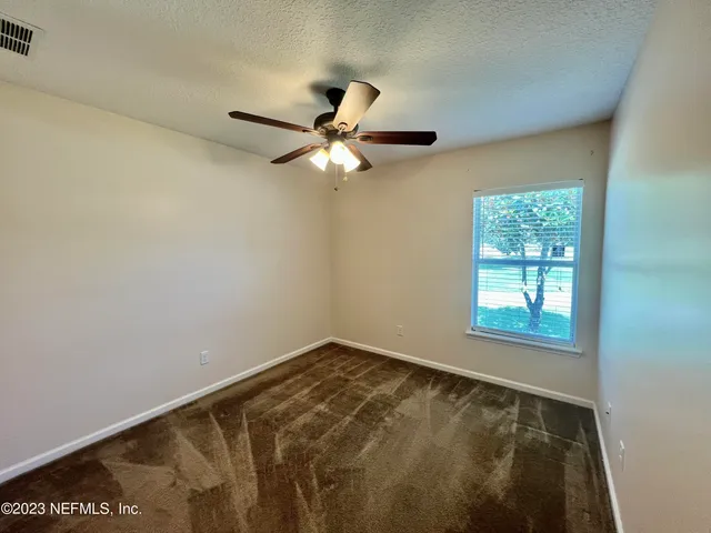 an empty room with a window and a fan