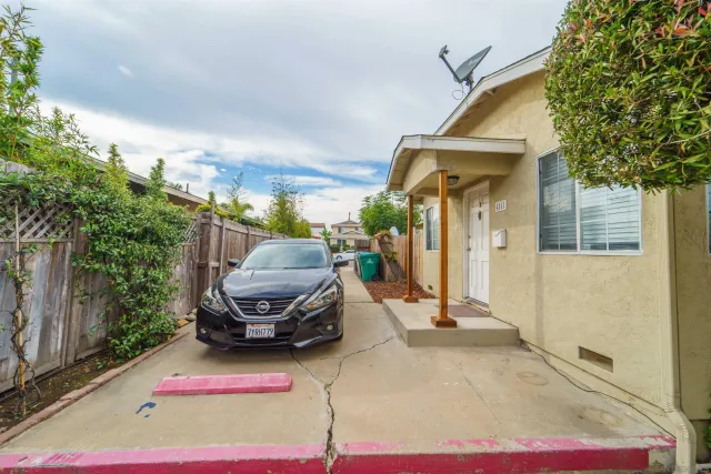 a view of a white house with a sink and lawn chairs