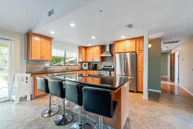 a kitchen with stainless steel appliances granite countertop a stove a sink a refrigerator and island