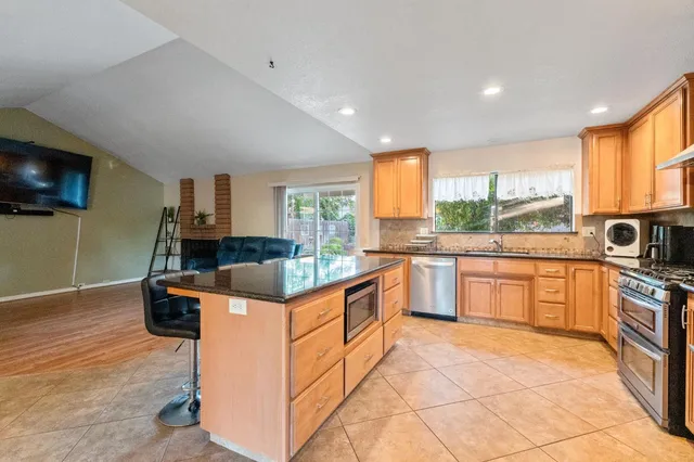 a kitchen with stainless steel appliances granite countertop a stove a sink and a microwave