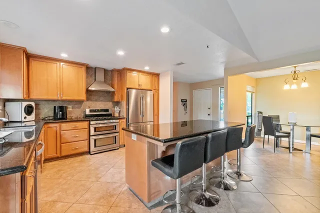 a kitchen with stainless steel appliances kitchen island granite countertop a refrigerator and microwave