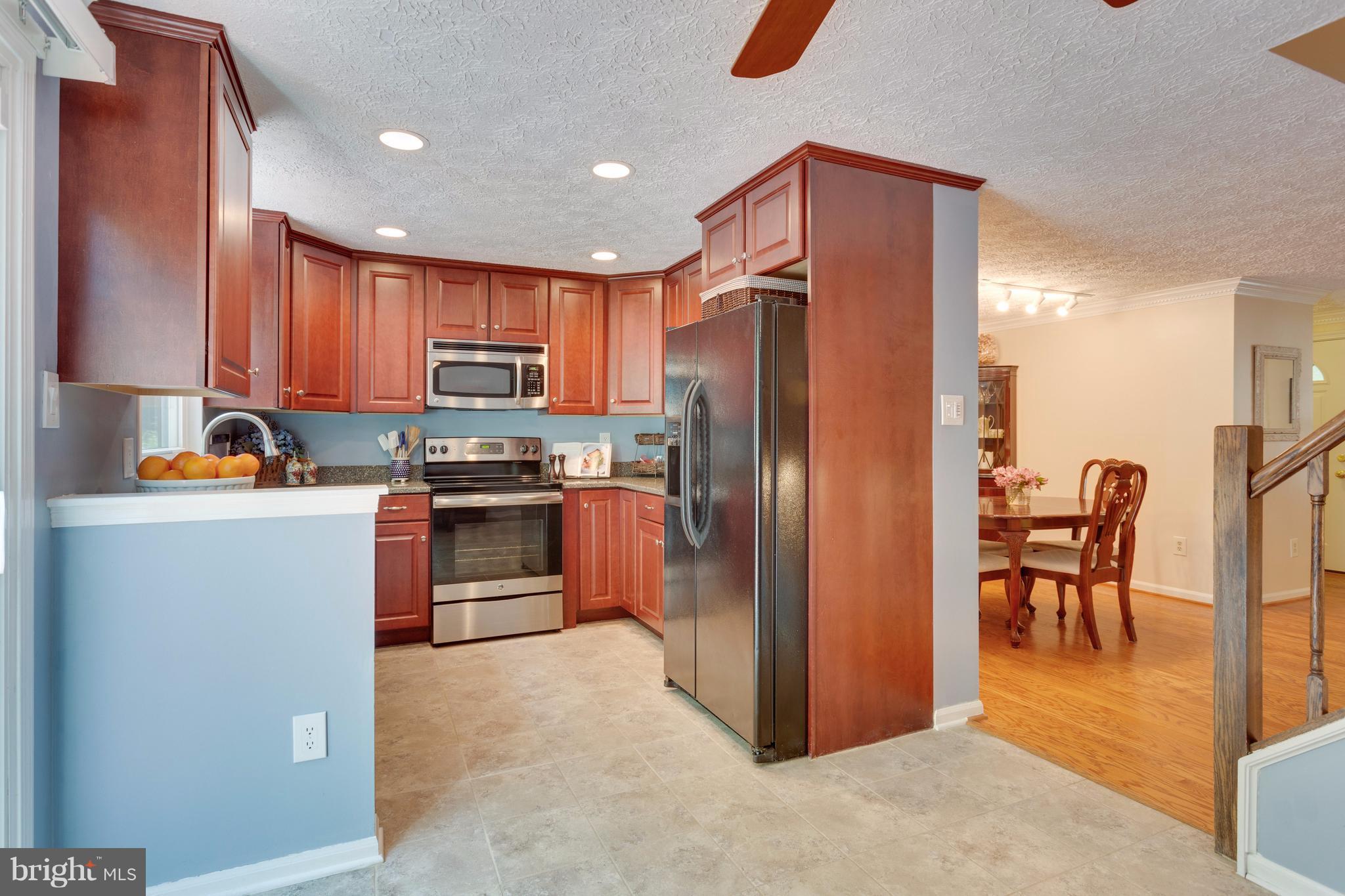6571 Forest Dew Court Springfield, VA 22152 - Photo 6 of 20 a kitchen with granite countertop a refrigerator and a stove top oven