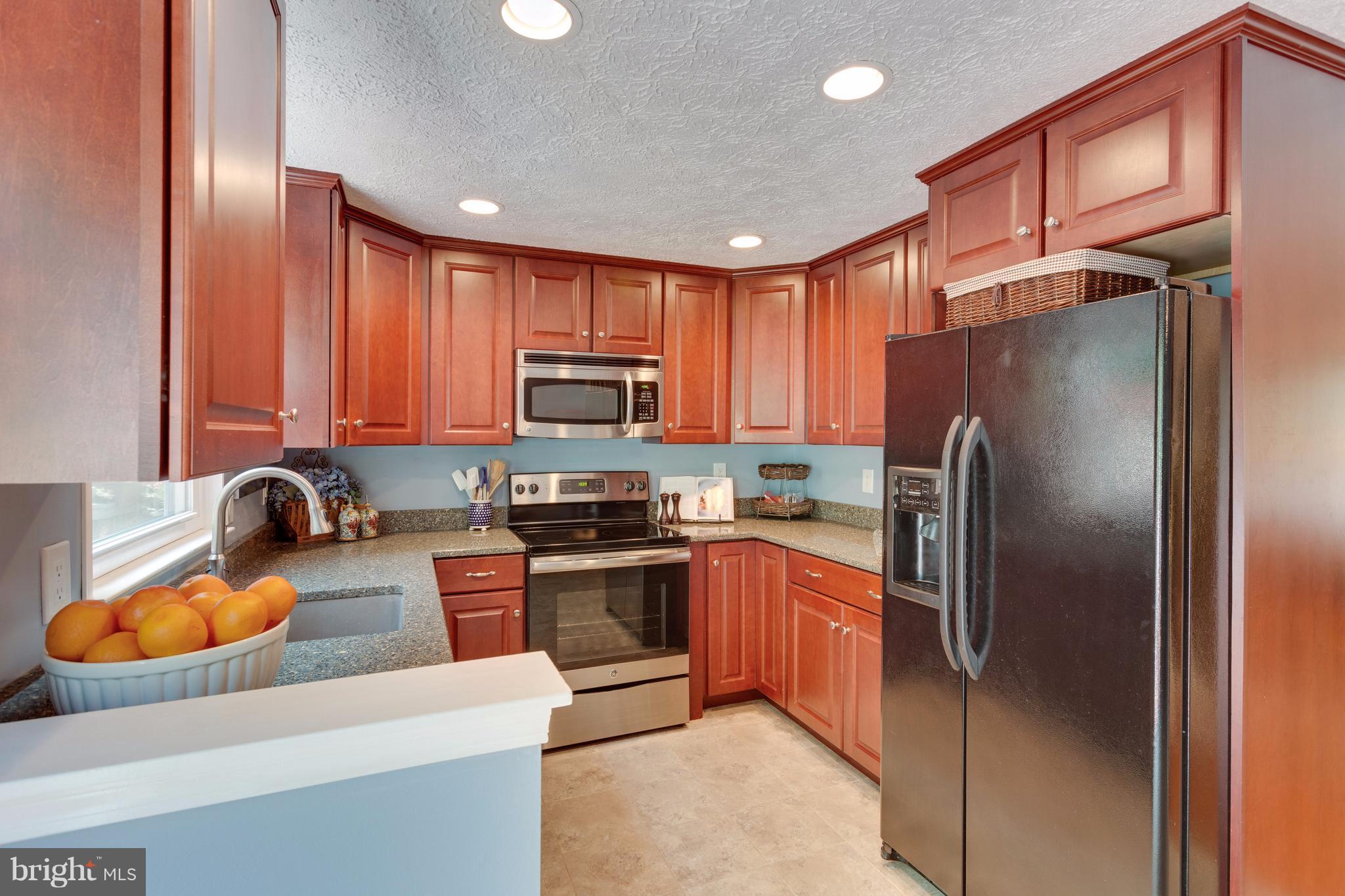 6571 Forest Dew Court Springfield, VA 22152 - Photo 7 of 20 a kitchen with stainless steel appliances granite countertop a refrigerator a stove top oven a sink and dishwasher