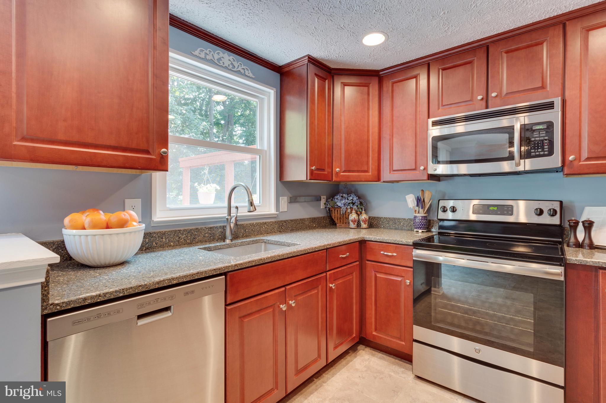 6571 Forest Dew Court Springfield, VA 22152 - Photo 8 of 20 a kitchen with granite countertop wooden cabinets a stove and a sink