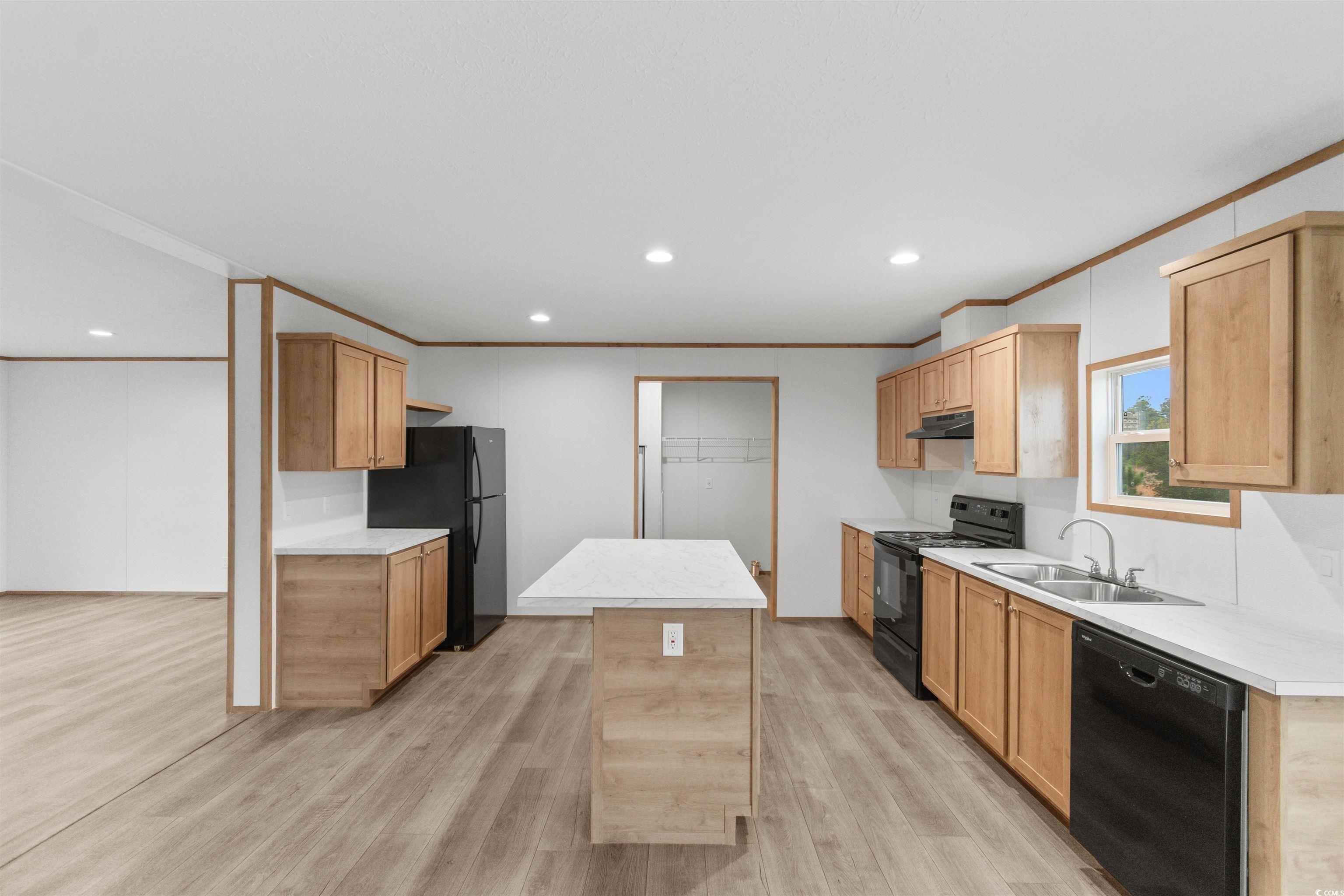 6613 Strickland Road Green Sea, SC 29545 - Photo 11 of 38 Kitchen with black appliances, light wood finished floors, light countertops, crown molding, and recessed lighting