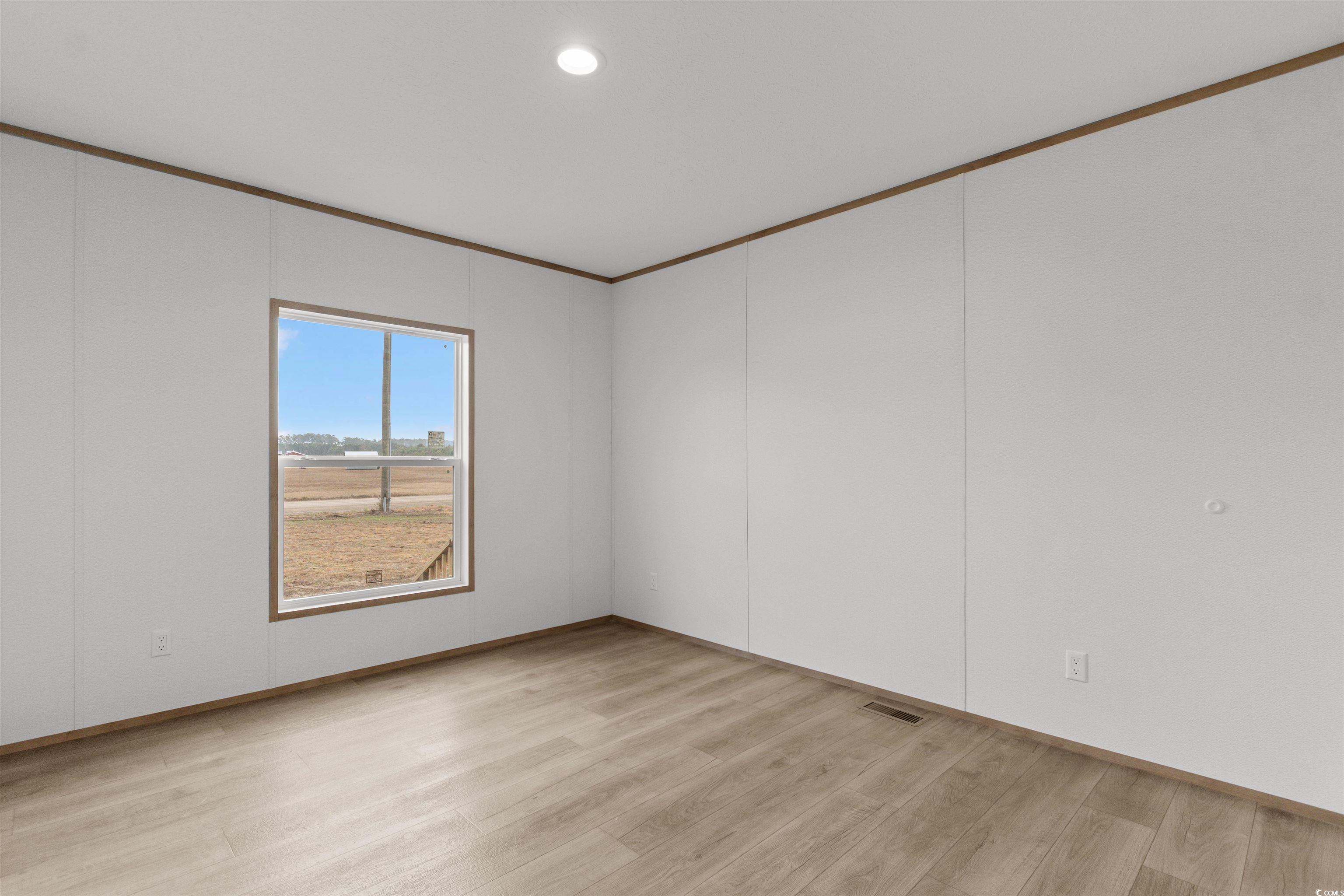 6613 Strickland Road Green Sea, SC 29545 - Photo 19 of 38 Unfurnished room featuring crown molding, light wood-style flooring, recessed lighting, and a decorative wall