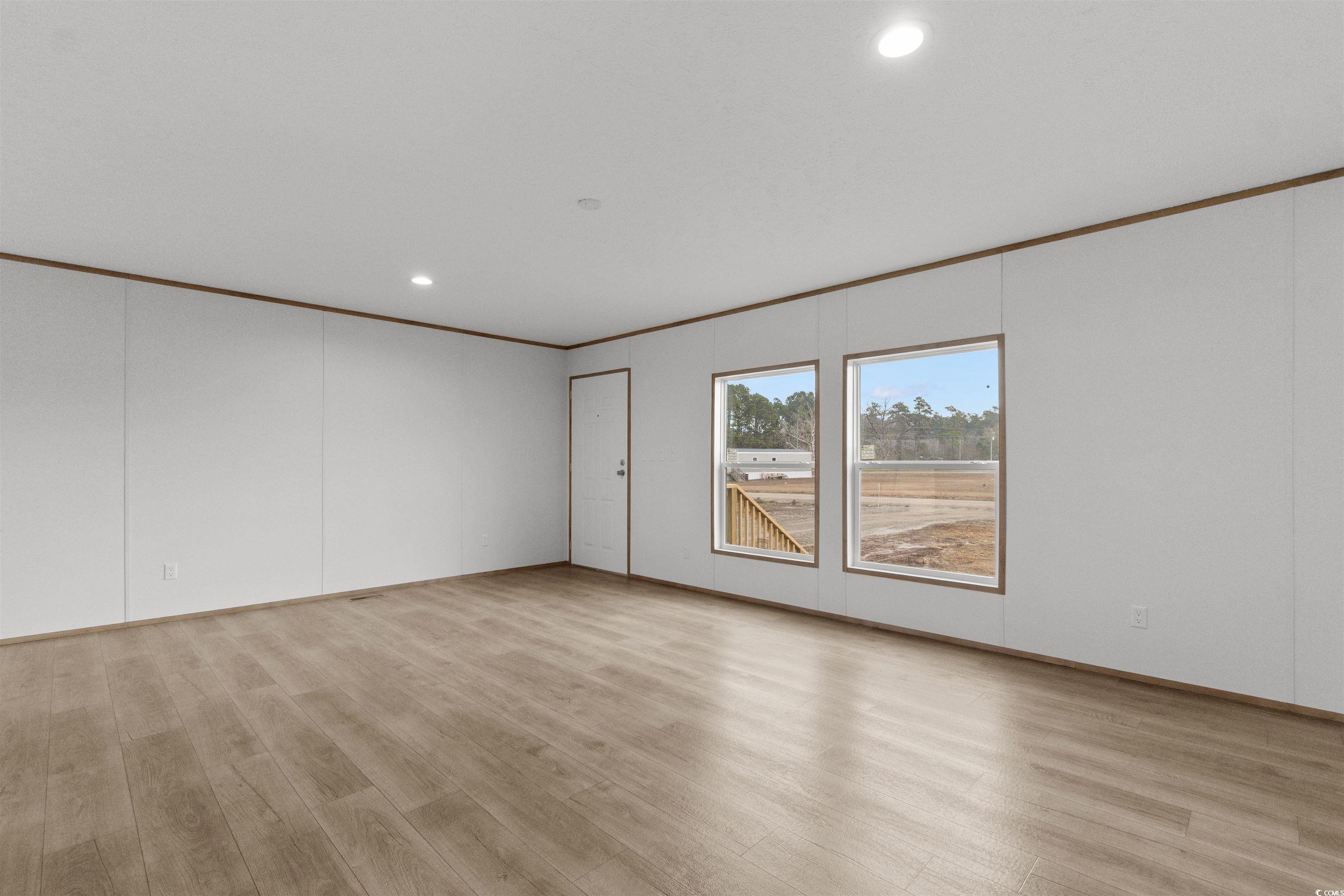 6613 Strickland Road Green Sea, SC 29545 - Photo 6 of 38 Empty room featuring crown molding, light wood-style flooring, recessed lighting, and a decorative wall