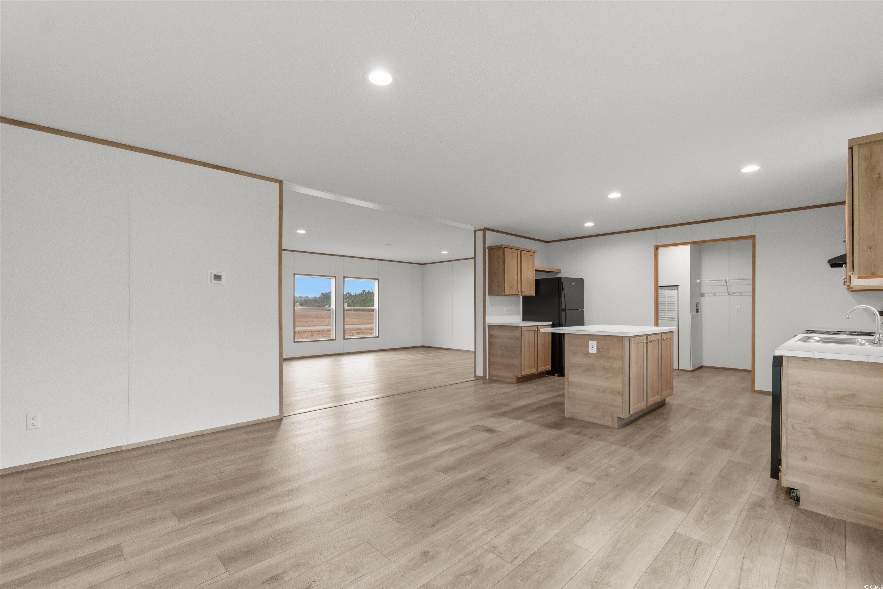 6613 Strickland Road Green Sea, SC 29545 - Photo 38 of 38 Kitchen featuring crown molding, light wood-style flooring, recessed lighting, open floor plan, and freestanding refrigerator