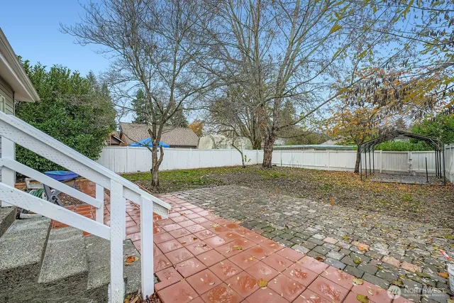 a view of a backyard with table and chairs under a large tree